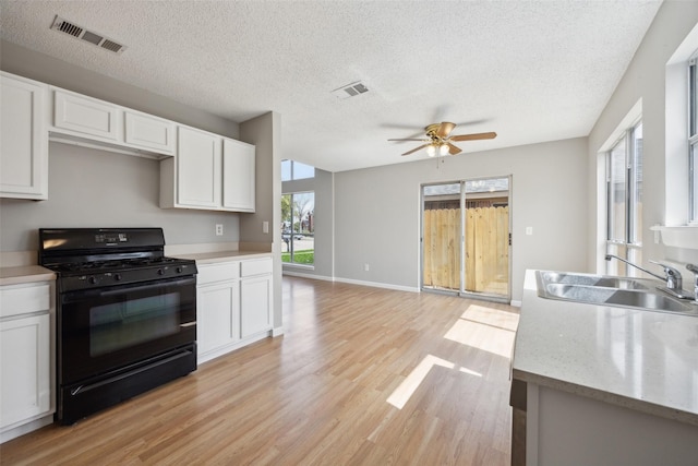 kitchen with a sink, visible vents, black gas range oven, and light countertops