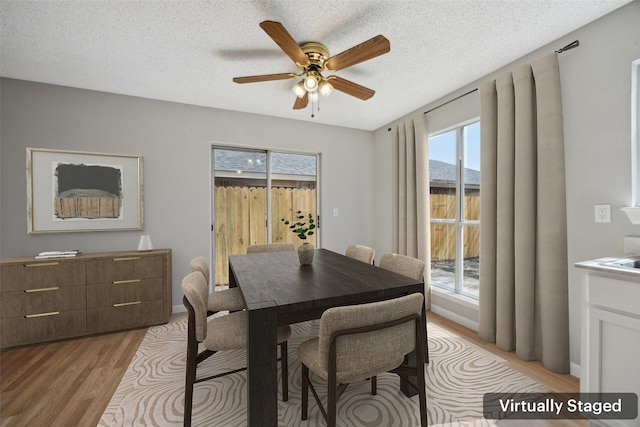 dining space with baseboards, a ceiling fan, light wood-type flooring, and a textured ceiling