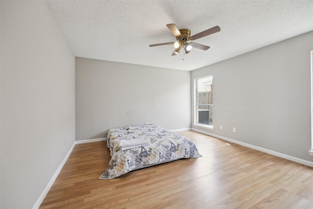 bedroom with wood finished floors, baseboards, and a textured ceiling