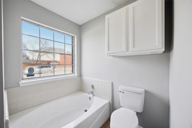 full bathroom with a textured ceiling, toilet, and a garden tub