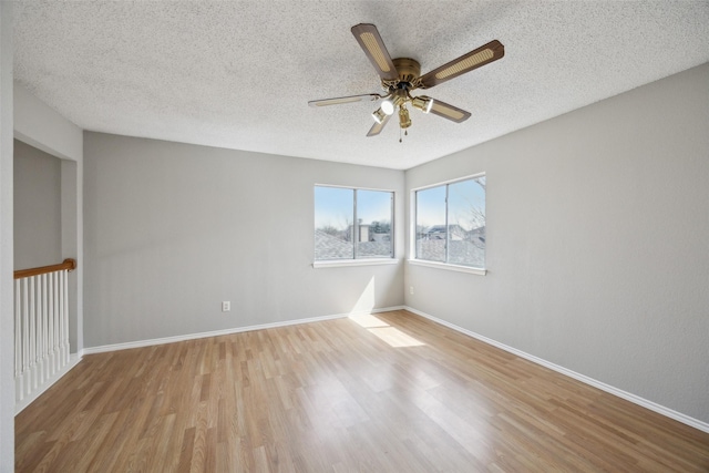 spare room featuring a textured ceiling, wood finished floors, baseboards, and ceiling fan