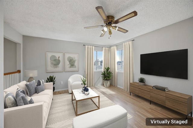 living room with a textured ceiling, light wood-style flooring, and ceiling fan