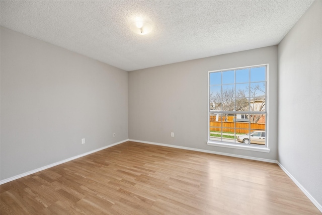 spare room featuring baseboards, a textured ceiling, and light wood-style flooring