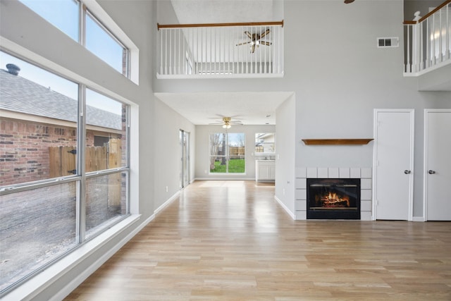 unfurnished living room with visible vents, baseboards, wood finished floors, and a fireplace