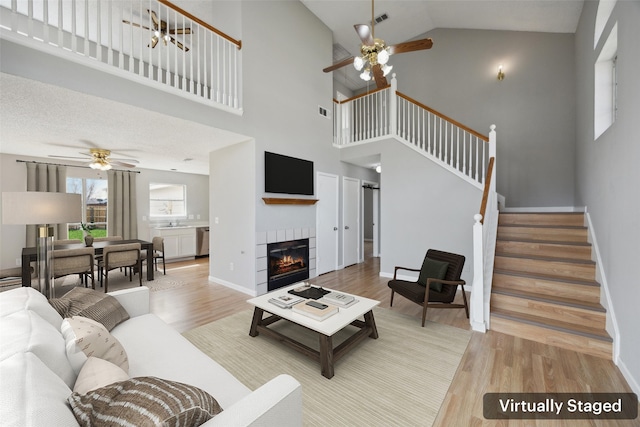 living room with stairway, visible vents, wood finished floors, and a tile fireplace