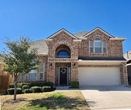 traditional-style house featuring an attached garage, fence, brick siding, and driveway