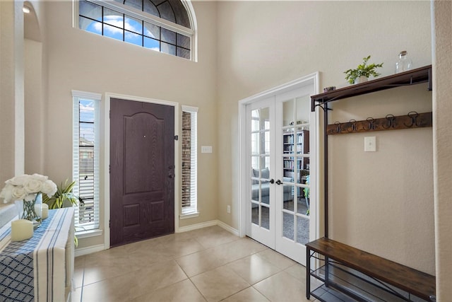 tiled entrance foyer featuring french doors, plenty of natural light, and a high ceiling