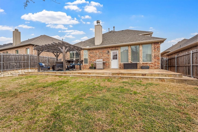 rear view of property featuring a yard, brick siding, a patio area, and a pergola