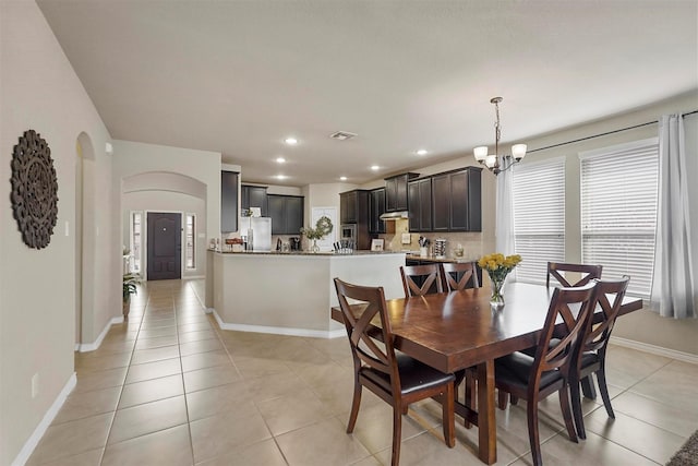 dining room with baseboards, light tile patterned floors, recessed lighting, an inviting chandelier, and arched walkways