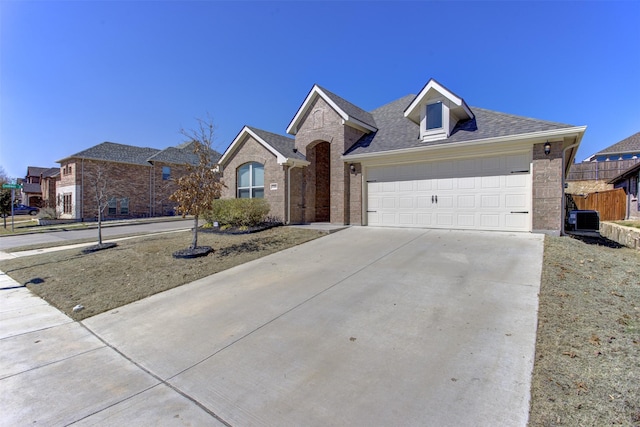 ranch-style home with fence, a shingled roof, concrete driveway, a garage, and brick siding