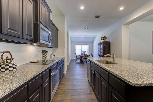 kitchen featuring visible vents, a sink, tasteful backsplash, dark wood-style floors, and appliances with stainless steel finishes