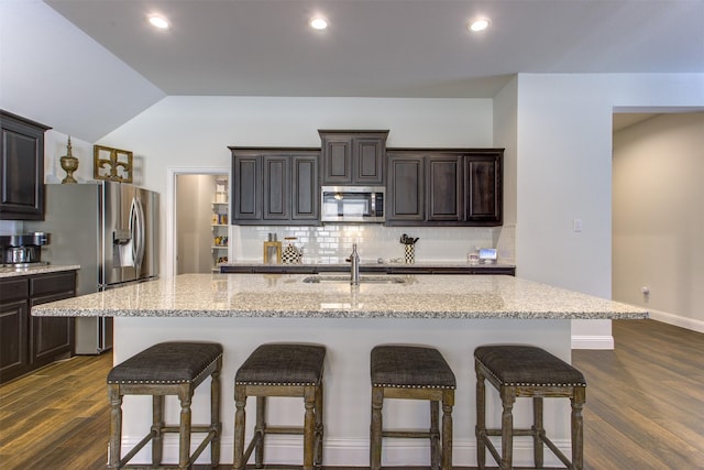 kitchen with a sink, decorative backsplash, a kitchen breakfast bar, and stainless steel appliances