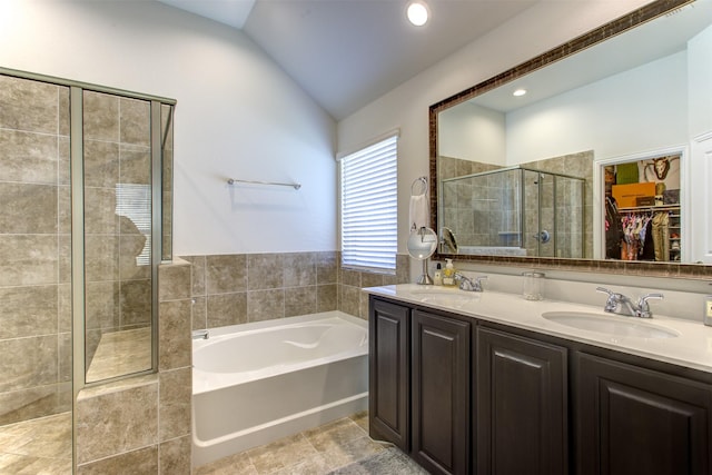 bathroom with a shower stall, a bath, vaulted ceiling, and a sink