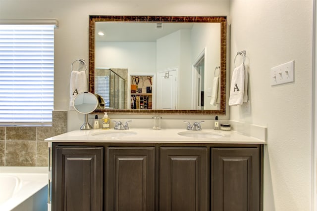 full bathroom featuring a garden tub, double vanity, a stall shower, and a sink