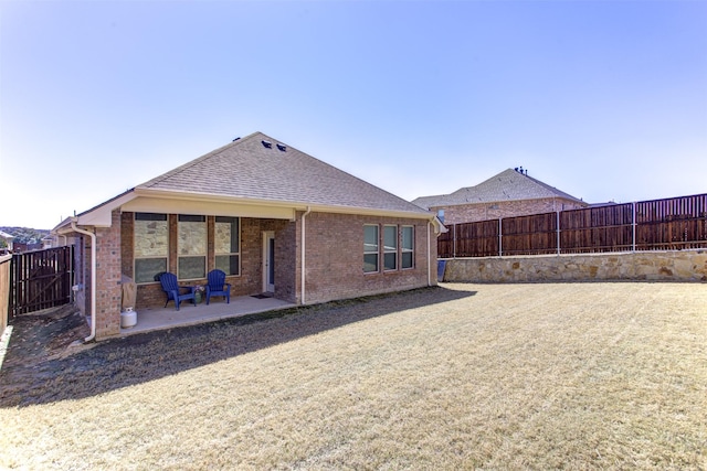 back of house with a patio area, brick siding, a fenced backyard, and roof with shingles