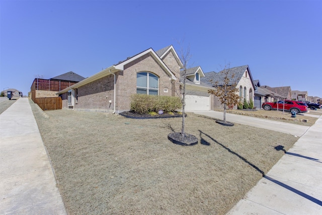 ranch-style home featuring a residential view, brick siding, an attached garage, and driveway