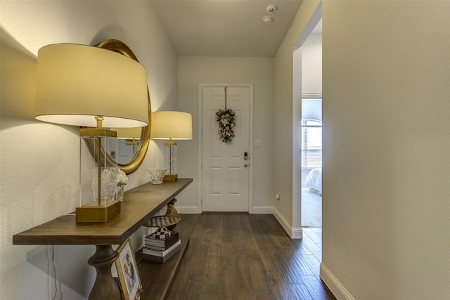 foyer entrance with dark wood finished floors and baseboards