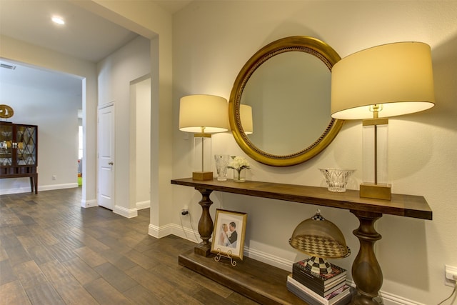 hallway with visible vents, baseboards, and dark wood-style flooring