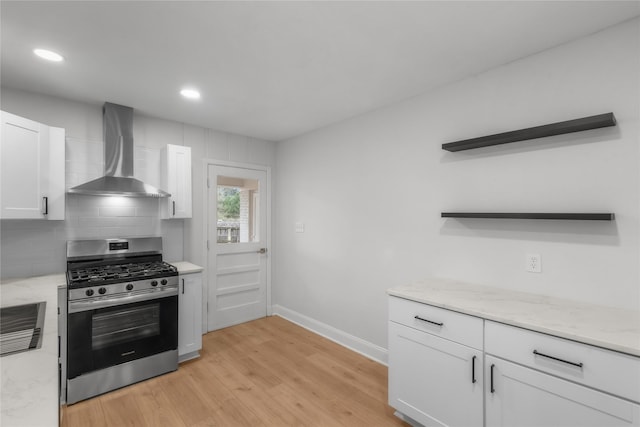 kitchen with light wood finished floors, gas range, white cabinets, wall chimney exhaust hood, and open shelves