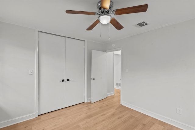 unfurnished bedroom featuring baseboards, visible vents, a closet, crown molding, and light wood-type flooring