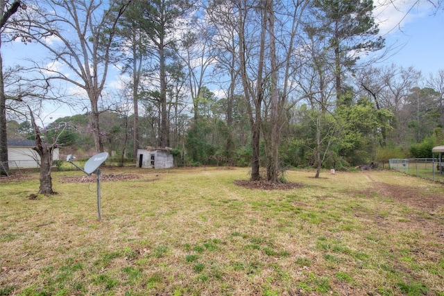 view of yard featuring a storage unit, an outbuilding, and fence