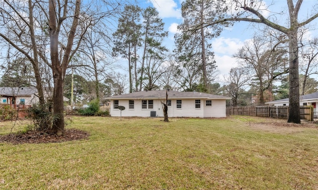 rear view of house featuring central AC unit, a lawn, and fence