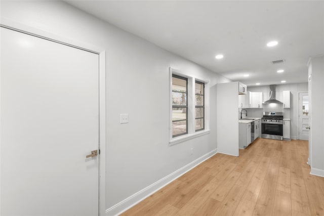 kitchen with light wood finished floors, visible vents, wall chimney range hood, light countertops, and appliances with stainless steel finishes