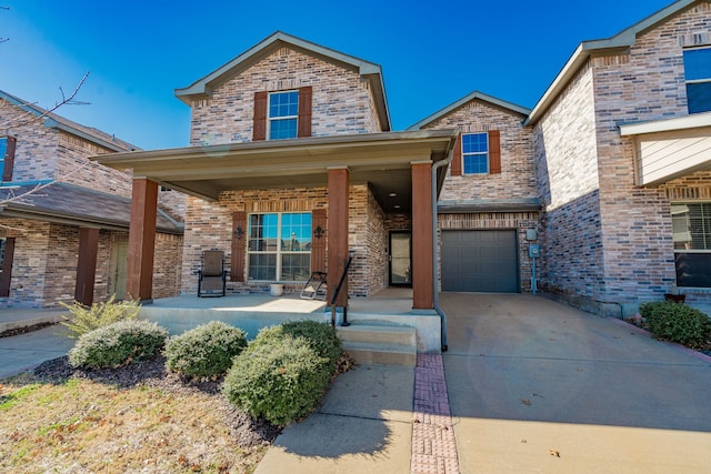 traditional-style home with brick siding, covered porch, driveway, and a garage