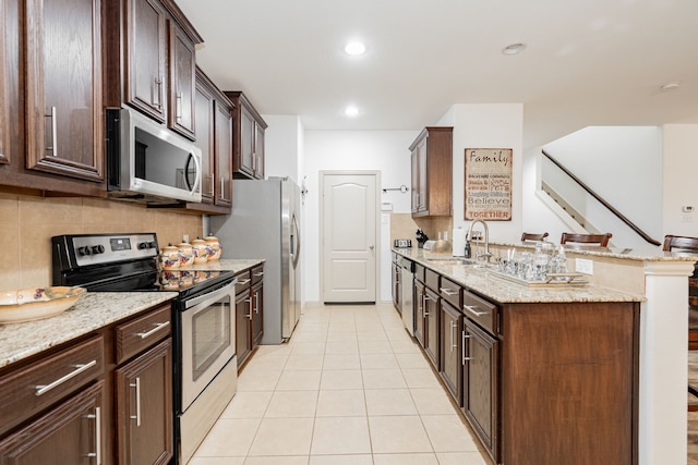 kitchen with backsplash, light tile patterned floors, a peninsula, stainless steel appliances, and a sink