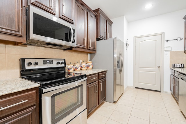 kitchen with decorative backsplash, light tile patterned floors, dark brown cabinets, and appliances with stainless steel finishes