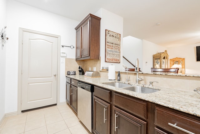 kitchen with light tile patterned floors, light stone countertops, a sink, dark brown cabinetry, and dishwasher