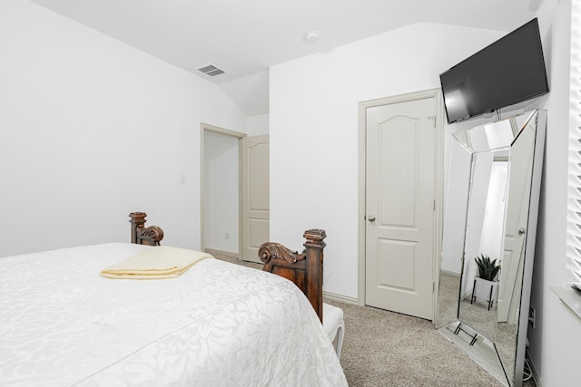 bedroom with visible vents, lofted ceiling, and light carpet