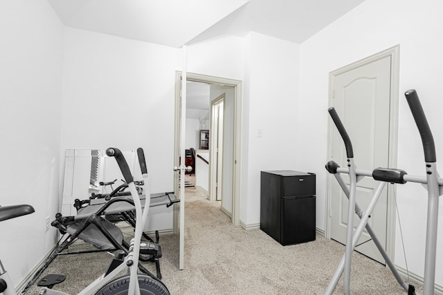 workout area featuring baseboards and light carpet