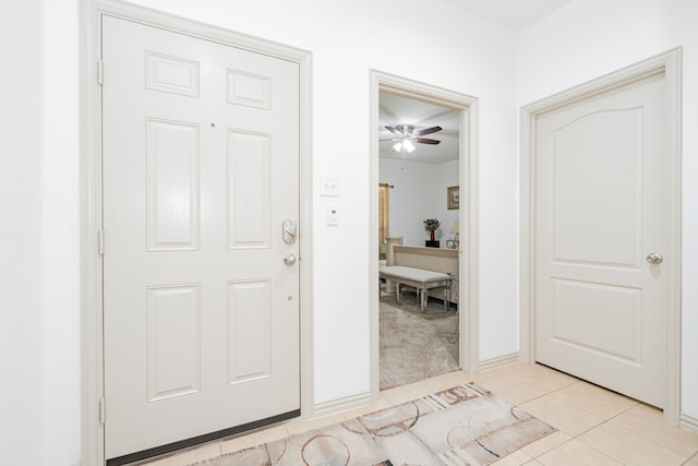 foyer entrance featuring light carpet, light tile patterned floors, baseboards, and ceiling fan