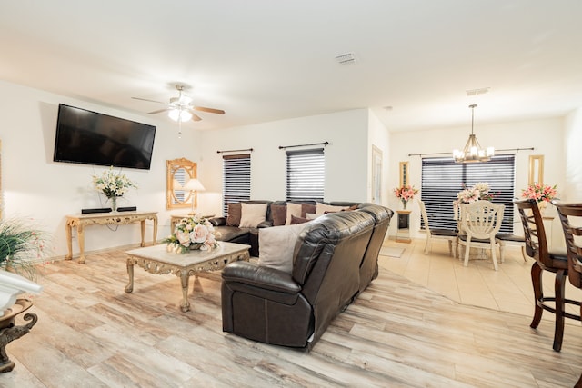 living area featuring visible vents, ceiling fan with notable chandelier, and light wood-style flooring