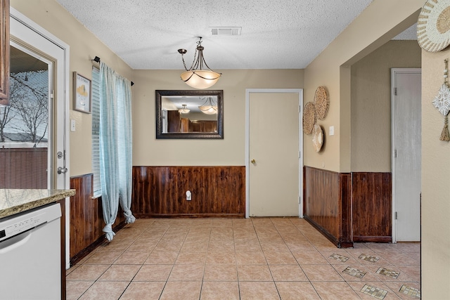 dining room with a wainscoted wall, a textured ceiling, and wood walls