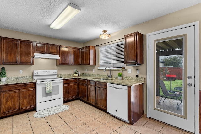 kitchen with under cabinet range hood, light tile patterned flooring, white appliances, a textured ceiling, and a sink