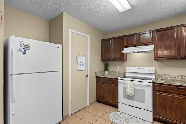 kitchen with under cabinet range hood, dark brown cabinetry, light countertops, light tile patterned floors, and white appliances