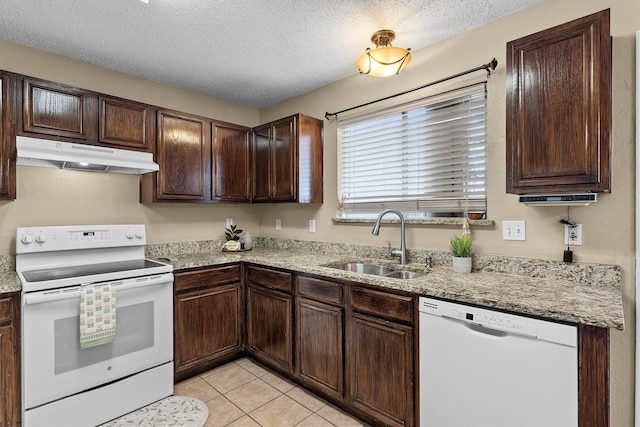 kitchen featuring under cabinet range hood, a sink, a textured ceiling, white appliances, and dark brown cabinetry