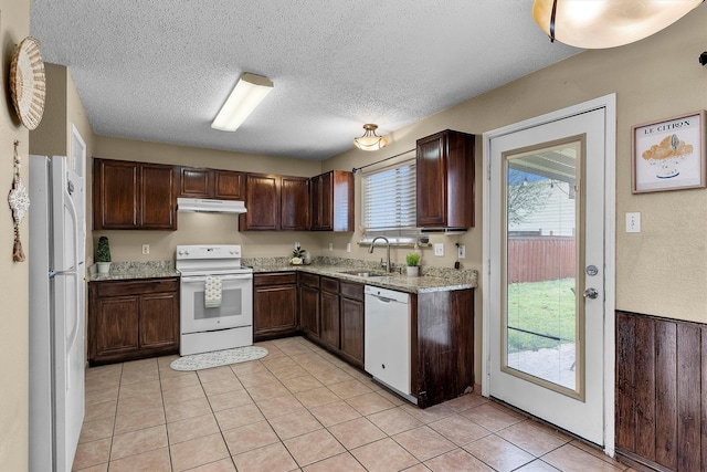 kitchen featuring under cabinet range hood, a sink, white appliances, dark brown cabinets, and a healthy amount of sunlight