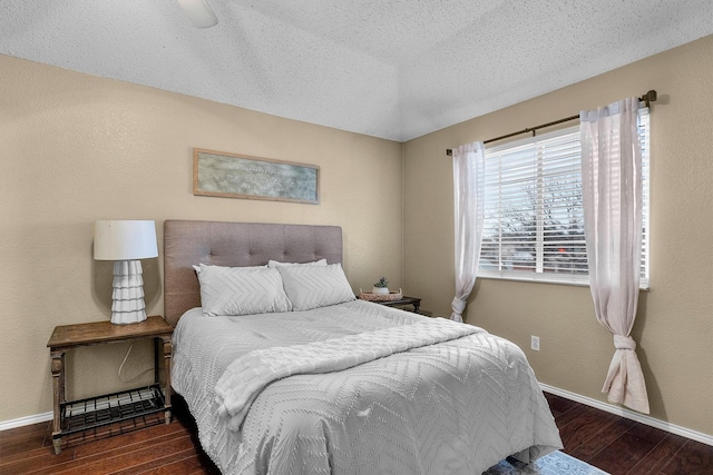 bedroom with wood finished floors, baseboards, a textured wall, and a textured ceiling