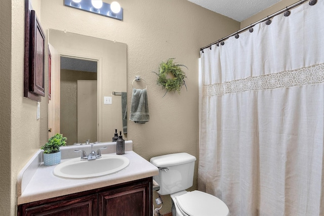 bathroom featuring vanity, a shower with shower curtain, toilet, and a textured wall