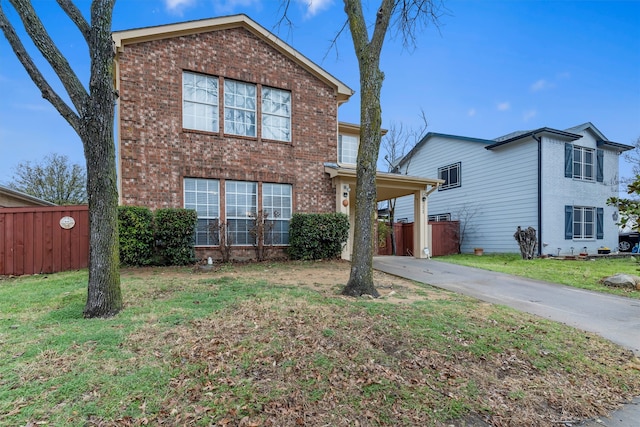 traditional-style house featuring brick siding, fence, a front yard, a carport, and driveway