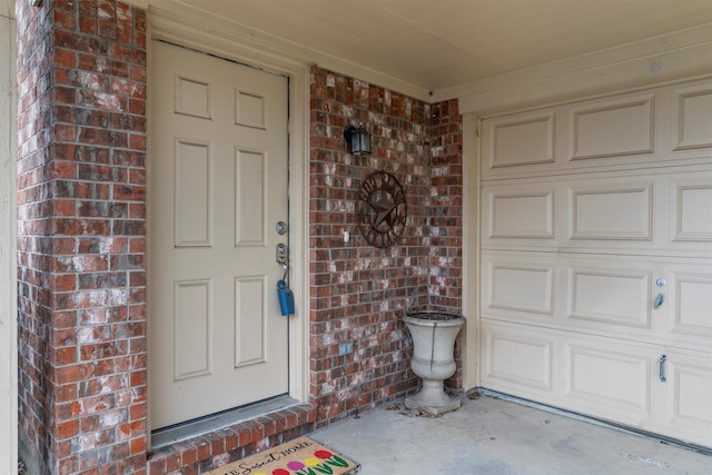 property entrance with a garage and brick siding