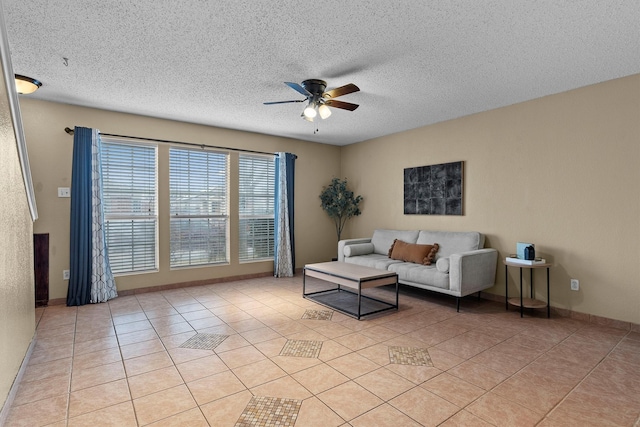 living area with light tile patterned floors, a ceiling fan, baseboards, and a textured ceiling