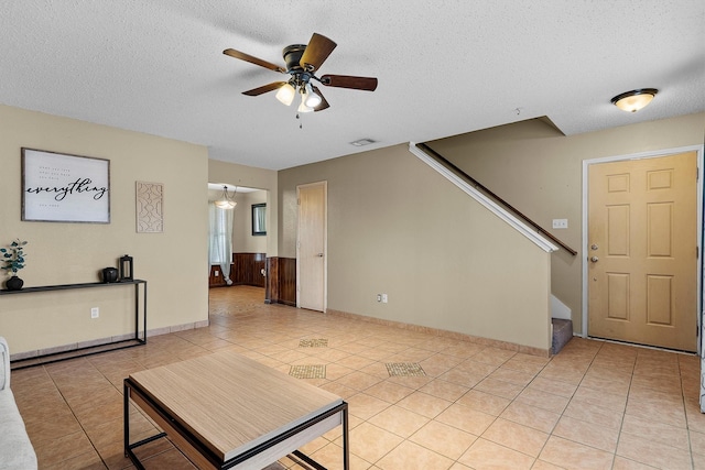 living room featuring light tile patterned flooring, visible vents, stairway, and a textured ceiling