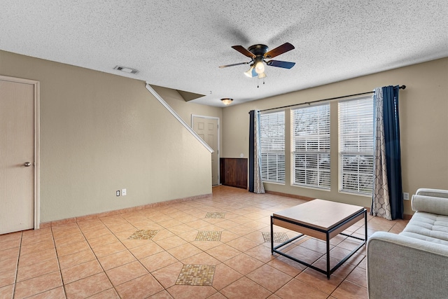 unfurnished living room featuring visible vents, a textured ceiling, light tile patterned flooring, and a ceiling fan