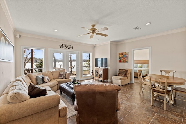 living room featuring visible vents, a healthy amount of sunlight, ornamental molding, and a ceiling fan