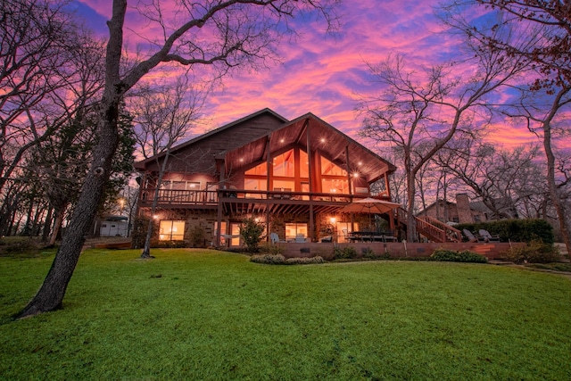 back of house at dusk with a yard, a deck, and stairway