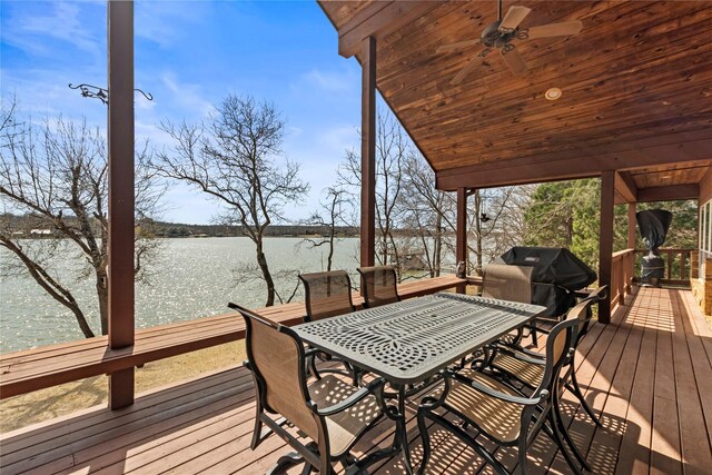 deck with outdoor dining area, a ceiling fan, a water view, and a grill